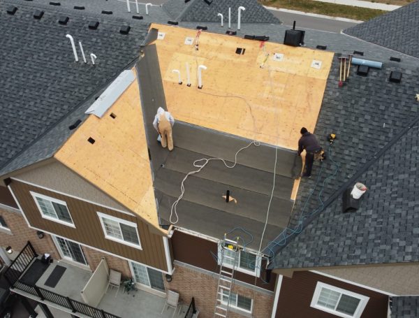 professional roofing crew installing asphalt shingles on house roof