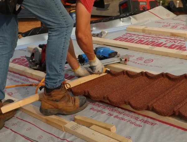 Roofing contractor installing metal roof panels on house