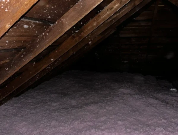 technician installing blown-in insulation in attic