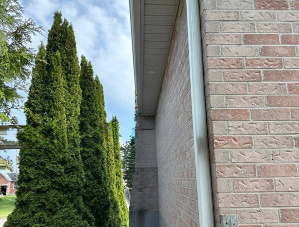 Contractor installing eavestrough along roof edge for water drainage